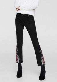 Czarne dżinsy z denimu z haftem kwiatowym w czerwieni i bieli na brzegach, slim fit, o długości  cropped z delikatnym rozszerzeniem.