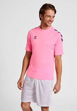 T-shirt de sport rose avec des accents noirs, à manches courtes et col rond, associé à un short blanc, fabriqué en matériau léger et respirant.