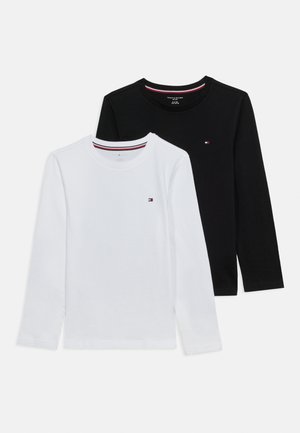 Dwie koszulki z długim rękawem i okrągłym dekoltem, jedna czarna, druga biała, każda z małym logo w kolorach czerwonym, białym i niebieskim na lewej piersi.