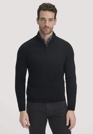 Schwarzer Pullover mit hohem Kragen und Viertelreißverschluss, ausgestattet mit langen Ärmeln und einer figurnahen Passform. Glatte Textur mit minimalen Details.