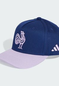 Gorra azul con visera lavanda, con un gran bordado de un gallo rosa en la parte delantera y el logo de tres rayas en el lateral.