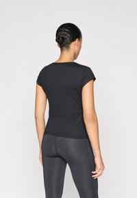 Μαύρο εφαρμοστό κοντομάνικο μπλουζάκι από απαλό βαμβάκι, με στρογγυλή λαιμόκοψη και ραφή χωρίς ραφές στους ώμους. Φοριέται με σκούρο κολάν.