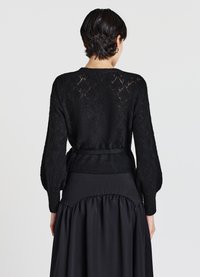 Cardigan nero lavorato a maglia con motivo a rombi, dotato di vita aderente, maniche lunghe a palloncino e finitura testurizzata.