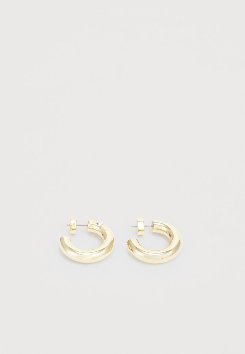 Gold-tone hoop earrings with a smooth, polished finish. Features a curved design and a small accent near the post for added detail.