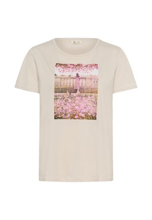 Tricou bej cu o imprimare pătrată a unei femei în rochie roz, stând lângă o balustradă de piatră cu vedere către o grădină cu flori roz.