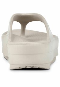 Šviesiai ruda šlepetė su lygiu paviršiumi, atvira nugara ir ergonomišku dizainu, turinti dvi išpjovas oro pralaidumui ir tekstūruotą pado dalį.
