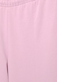 Světle růžové tepláky vyrobené z měkké látky, s elastickým pasem a hladkou strukturou s minimem švů.