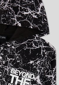 Hoodie nero con un motivo marmorizzato bianco, con una grafica frontale che recita "BEYOND THE." Realizzato in morbido cotone.
