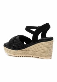 Sandali con tacco a cuneo neri caratterizzati da un design di cinturini intrecciati, dettagli in suede e una suola in juta testurizzata. Include una cinghia regolabile alla caviglia.