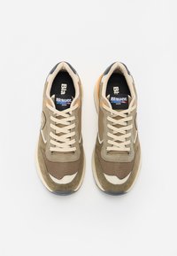 Sneakers in mesh e camoscio marroni con lacci e dettagli crema, caratterizzati da un logo nero sulla linguetta e una suola grigia testurizzata.