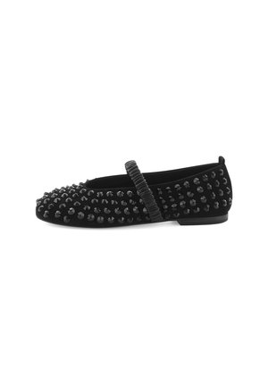 Black flat shoes made of soft material, featuring a studded design on the upper and a textured strap across the instep.