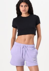 T-shirt noir court à manches courtes associé à un short de survêtement violet clair avec une taille élastique et des poches avant.