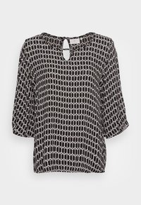 Blusa bianca e nera con scollatura a chiave, maniche 3/4 e motivo geometrico a nido d'ape. Tessuto leggero e liscio con una leggera lucentezza.