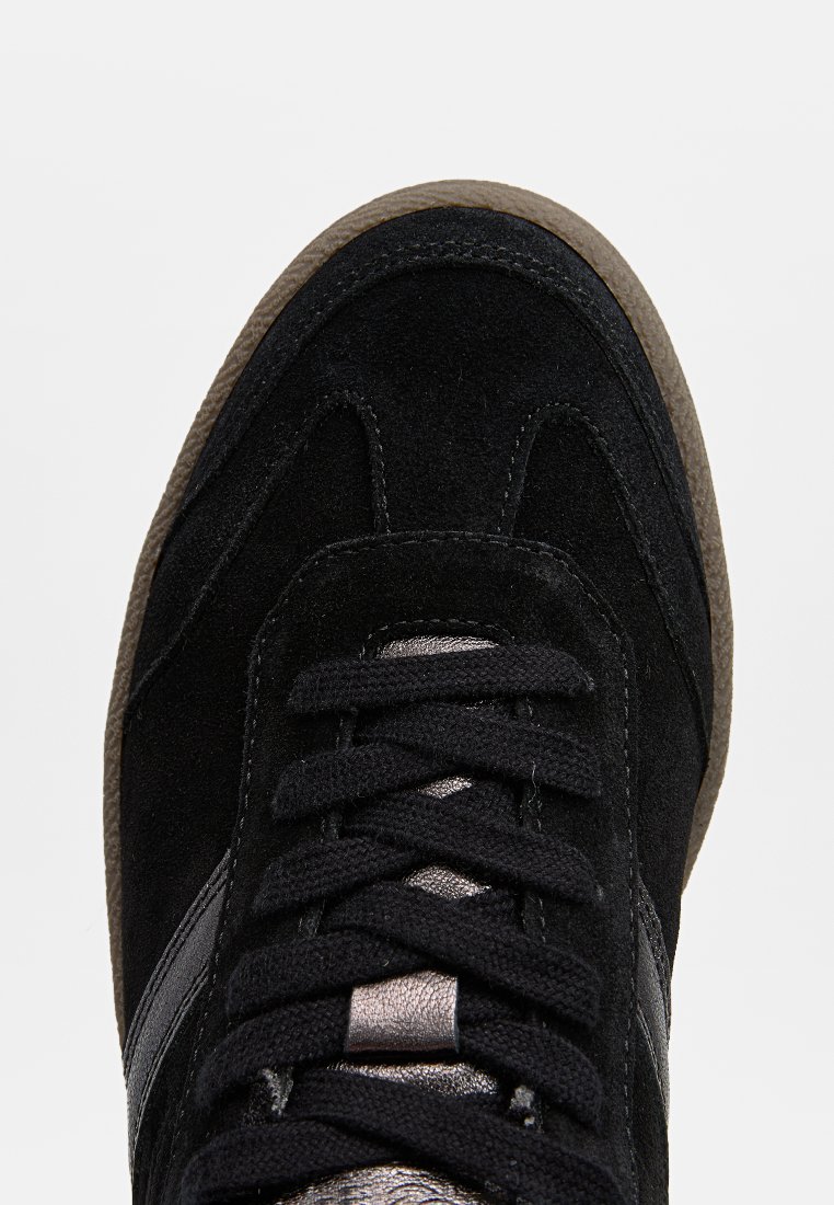 Schwarze Wildledersneaker mit einer strukturierten Oberfläche, schlankem Design und reflektierenden silbernen Akzenten an der Seite. Dunkle Schnürung und Gummisohle.