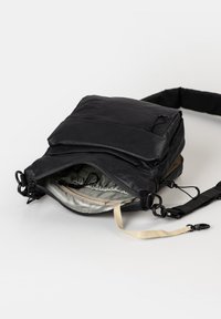Schwarze Tasche mit strukturiertem Äußeren, ausgestattet mit einer Vordertasche und einem mit silbernem Stoff gefütterten, mit Reißverschluss versehenen Hauptfach. Verstellbarer Trageriemen enthalten.