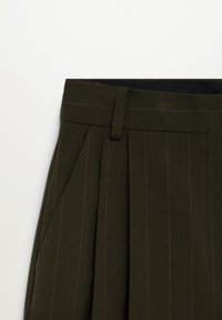 Pantalon à fines rayures vert olive foncé avec plis, passants de ceinture et poche latérale visible sur fond blanc.