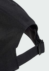 Crna kapa od teksturirane tkanine s zakrivljenim vizirjem, koja ima kopču s remenom i vidljive detalje šivanja.