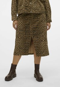 Leopardenmuster Rock in Beige und Schwarz, knielang mit einem Schlitz vorne. Kombiniert mit dunkelbraunen Stiefeletten. Glatte Textur, lässiges Design.
