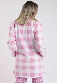 Camiseta de forro polar de cuadros en tonos rosa y blanco, con mangas largas y una parte trasera ligeramente alargada. Textura suave y diseño cálido.