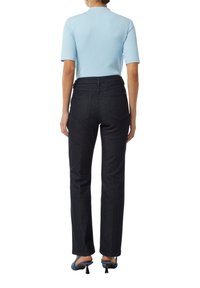 Niebieska, prążkowana bluzka z krótki rękawem, zestawiona z ciemnymi dżinsami. Spodnie mają prostą nogawkę i dwie tylne kieszenie. Buty mają mały obcas.