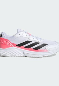Chaussure de sport blanche avec des accents roses et trois bandes noires sur le côté, dotée d'une semelle texturée et d'un design à lacets.