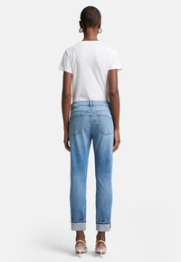Ljust blå denimjeans med rak passform, uppvikta fållar och två bakfickor, tillsammans med en vit t-shirt med kort ärm.