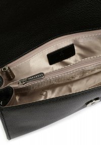 Interno di una borsa in pelle nera con texture, foderato in beige, dotato di un scomparto con zip e di un'etichetta in metallo argentato.
