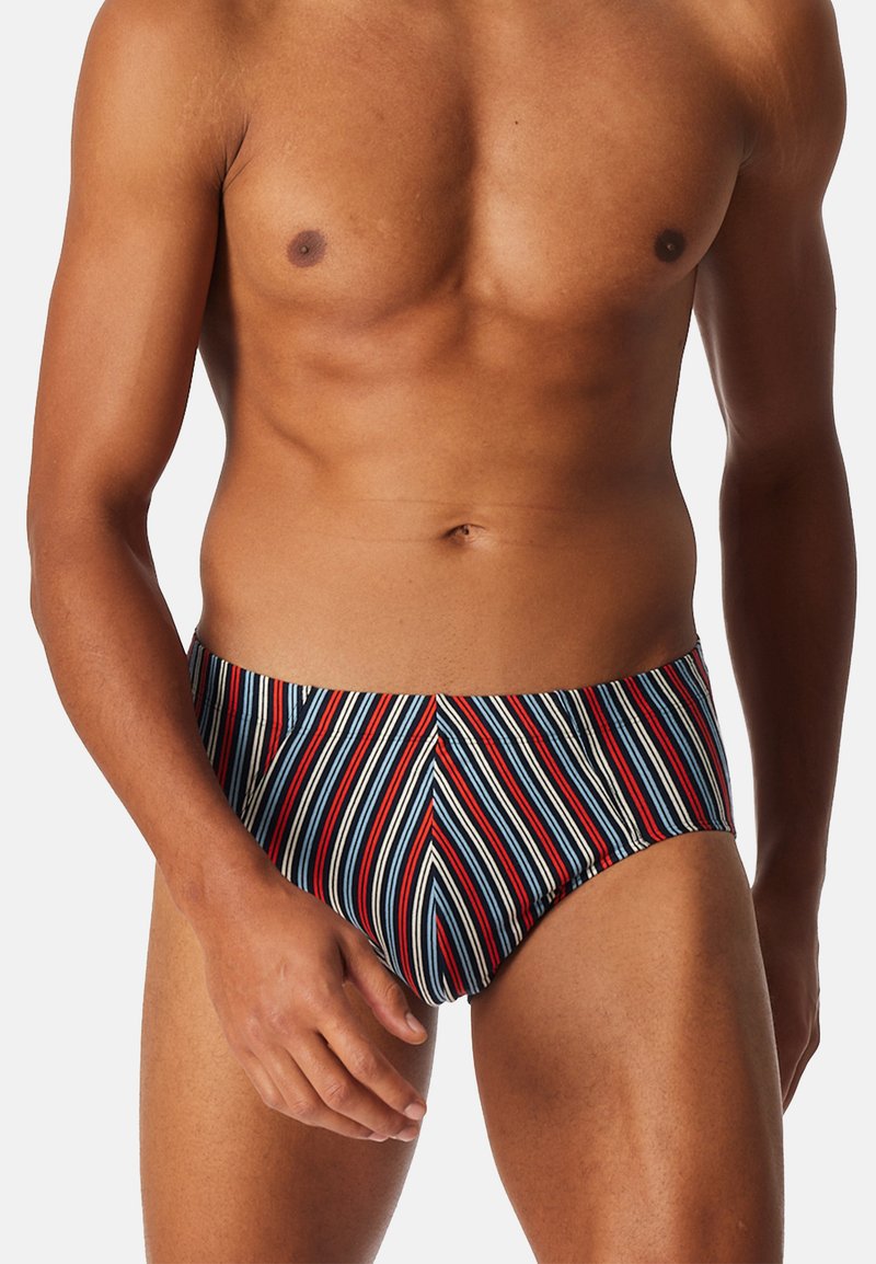 Slip de bain pour homme avec des rayures verticales bleu marine, rouge et blanc. Fabriqué en tissu extensible avec un design ajusté et une taille élastique.