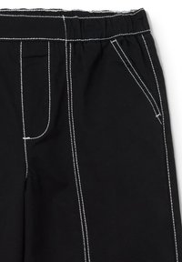 Zwarte broek met een elastische tailleband, voorzien van witte stiksels, een voorzak en een recht gesneden ontwerp. De stof lijkt op een katoenmix.
