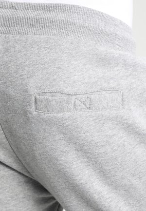Nærbillede af lysegrå sweatpants, der viser den bageste talje og en lille, horisontalt syet lomme detalje.