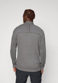 Pullover grigio a maniche lunghe con colletto alto, tessuto testurizzato e dettagli delle cuciture a contrasto. Presenta polsini aderenti e un orlo dritto.