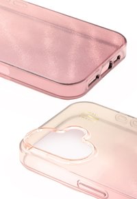 Przezroczyste różowe etui na telefon o brokatowej fakturze, z wycięciem w kształcie serca i małym złotym logo. Gładkie krawędzie i precyzyjne porty.