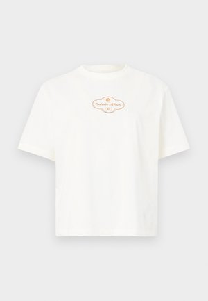 T-shirt de algodão branco com mangas curtas, apresentando uma gola redonda e uma etiqueta central com logótipo em tons bege e detalhes dourados.