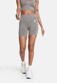 Sivé športové šortky vyrobené z textúrovanej tkaniny, priliehajúci strih, s vysokým pásom a detailom loga. Skombinované s bielymi teniskami a ponožkami.