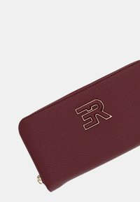 Portafoglio in pelle color bordeaux con finitura testurizzata e logo in tonalità oro sul davanti. Chiusura con cerniera e bordi lisci.
