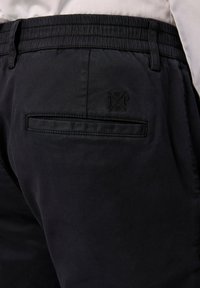 Pantaloni blu scuro con elastico in vita, dotati di una tasca posteriore con pattina rettangolare e logo ricamato sopra la tasca. Texture morbida.