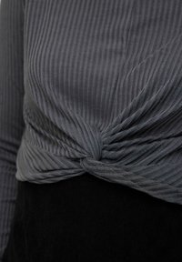 Pilkas juostuotas viršus su susukamu mazgeliu ties liemeniu, pagamintas iš tekstūruoto audinio; derinamas su juoda apatine dalimi.