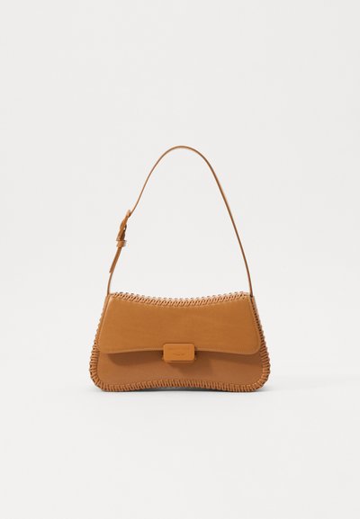 Sac à main en cuir tan avec un motif cousu le long des bords et une bandoulière réglable. Dispose d'une fermeture à rabat et d'une petite étiquette avec le logo.