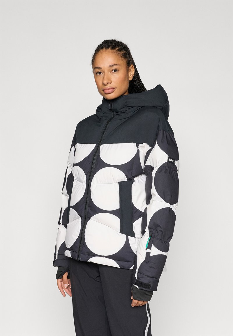 Zwart-wit donsjack met grote ronde patronen, voorzien van een capuchon, voorrits en zijzakken. Lichtgewicht, gewatteerd ontwerp.