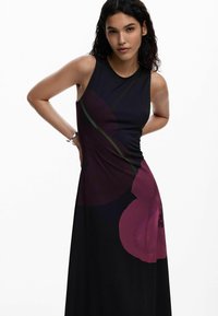 Czarna sukienka bez rękawów z dużymi ciemnofioletowymi kwiatowymi wzorami. Materiał jest gładki, o dopasowanym kroju i lekkim stretchu.