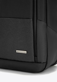 Zaino nero con un tessuto testurizzato e dettagli in pelle liscia, dotato di una piastra logo metallica e cuciture a contrasto.
