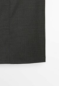 Tessuto grigio scuro con una superficie texturizzata, caratterizzato da cuciture verticali ordinati e un orlo dritto nella parte inferiore.