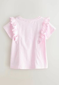 Maglietta rosa chiaro a maniche corte per bambino con rifinitura arricciata lungo i bordi del pannello frontale su sfondo neutro.