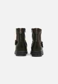 Botas de tornozelo em couro preto com fechos de zíper, salto texturizado e detalhe em fivela. Acabamento suave com desgaste mínimo na sola.