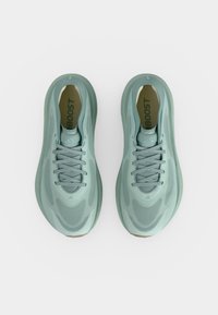 Ζευγάρι ανοιχτό πράσινα παπούτσια Adidas για τρέξιμο με ενισχυμένες BOOST εσωτερικές σόλες, επάνω μέρος από δίχτυ και σχεδιασμό με κορδόνια, εικόνα από πάνω σε λευκό φόντο.