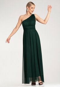Długa zielona sukienka na jedno ramię z lejącego materiału, z marszczonym dekoltem, dopasowaną talią i przezroczystą warstwą.