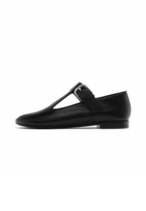 Black leather flat shoe with a T-bar design, featuring a side buckle and a textured finish, rounded toe, and low heel.