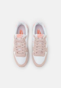 Baskets Nike avec une tige en mesh blanc et des superpositions en daim rose, présentant des accents roses et un design classique à lacets.
