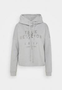 Felpa grigia corta in morbido tessuto, dotata di cappuccio con cordoncino e dettaglio in strass con il logo al centro. Maniche lunghe con polsini.