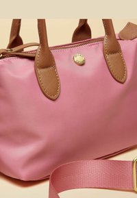 Borsa a mano in nylon rosa con dettagli in similpelle marrone, chiusura con zip, forma arrotondata e tracolla rosa rimovibile. Presenta un dettaglio logo dorato.